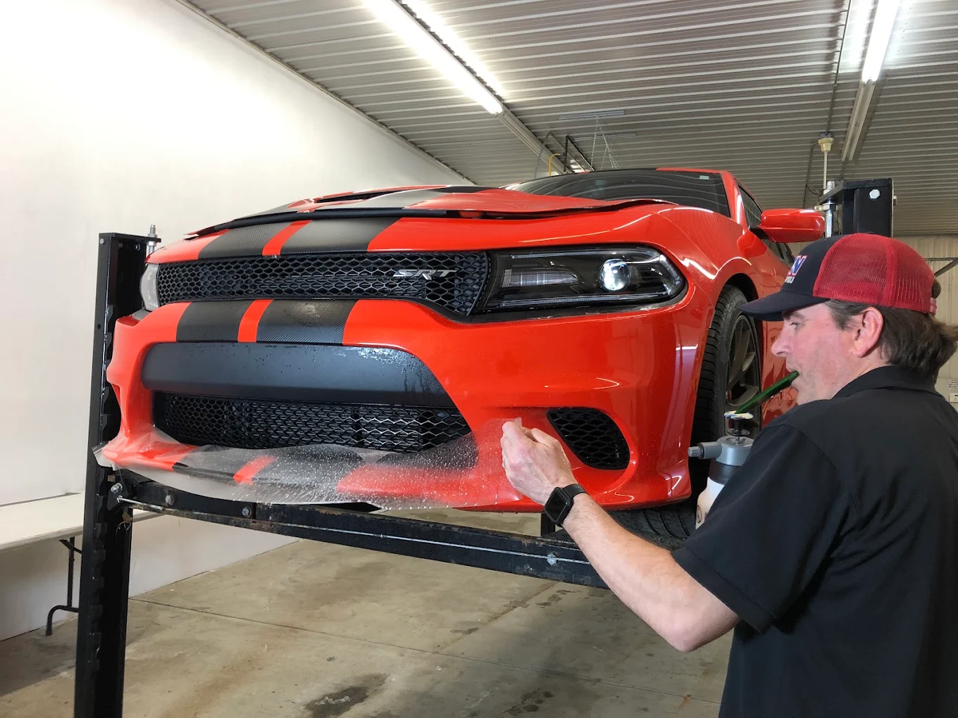 Paint protection film being installed on a red Dodge Charger
