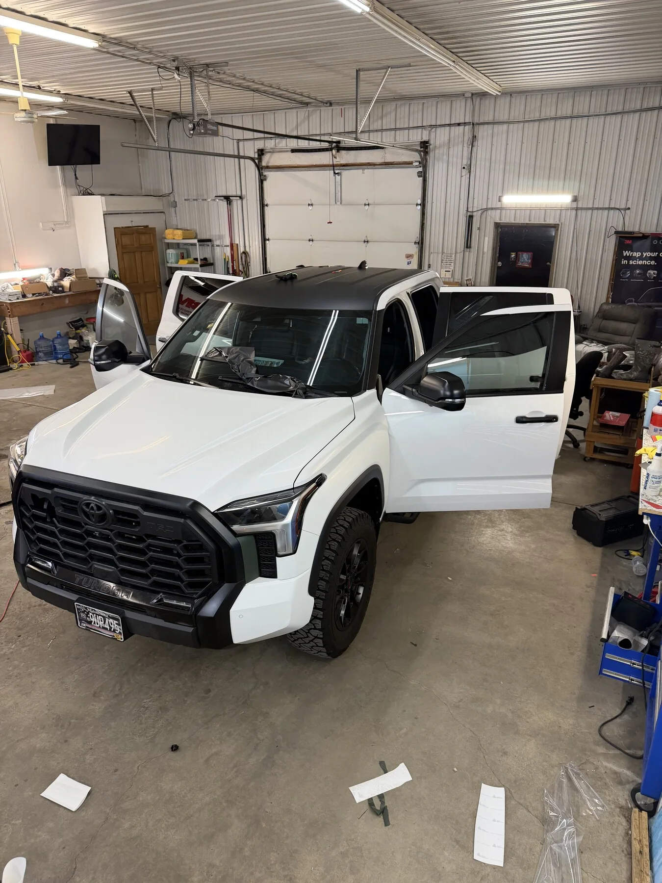 White pickup with doors open during window work