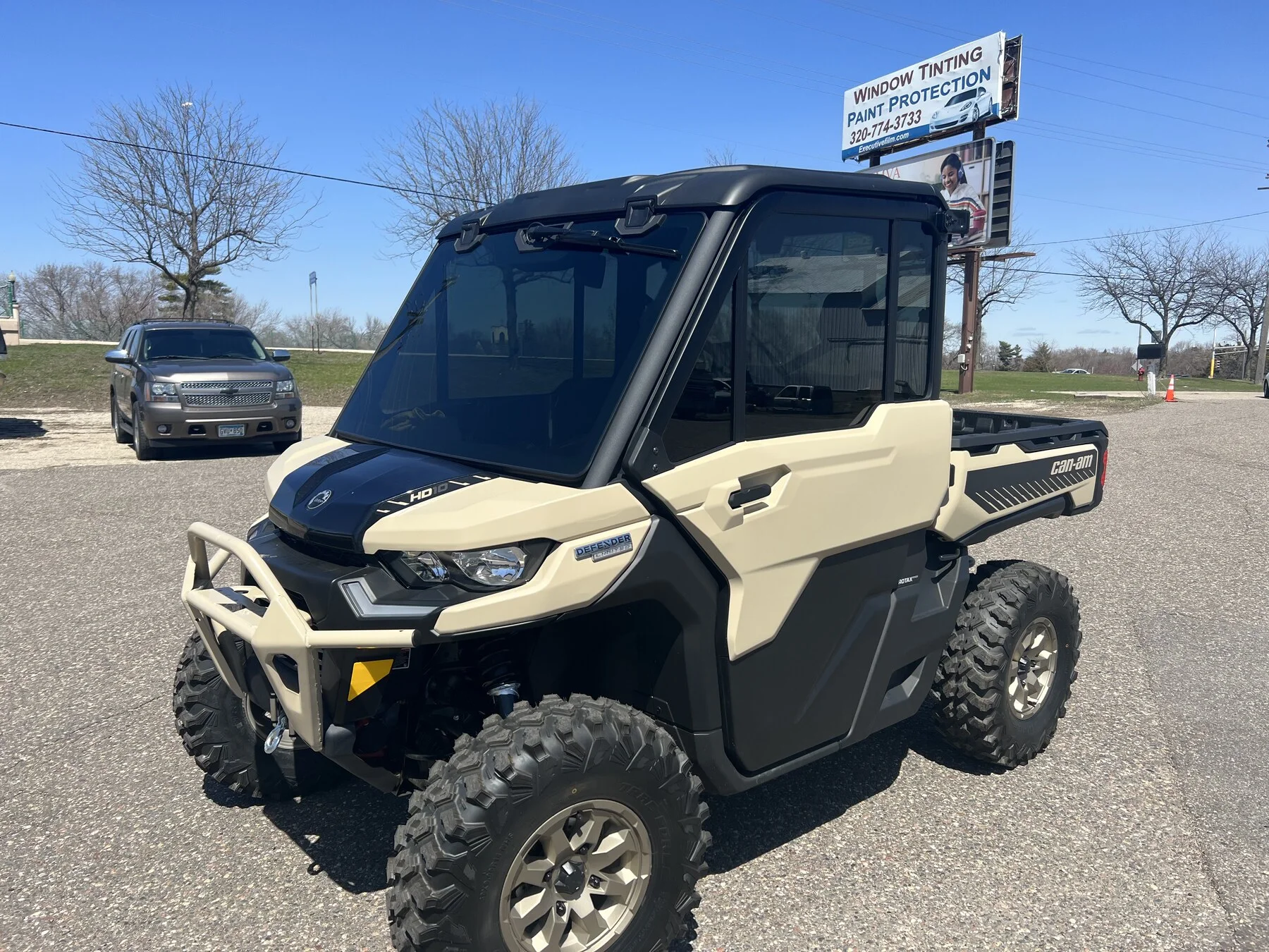 Tan enclosed-cab side-by-side outside the shop